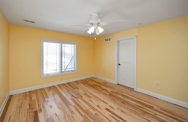 empty room with light wood-type flooring, visible vents, and baseboards