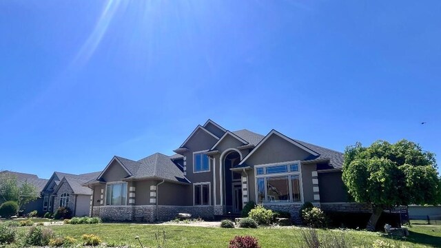 1205 NE 31st St, Ankeny, IA 50021 - view of front of home featuring stone siding, a front lawn, and stucco siding