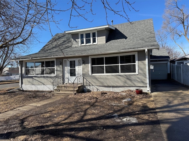 view of front of house featuring driveway, a shingled roof, and fence