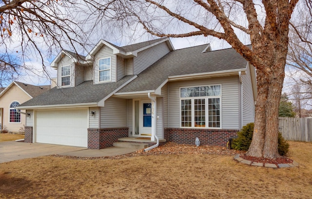 view of front of home featuring a shingled roof, brick siding, driveway, and fence