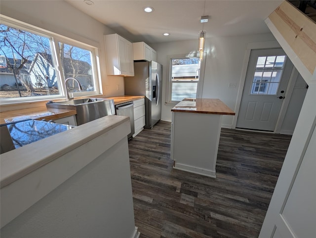 kitchen featuring dark wood-style floors, stainless steel appliances, butcher block counters, white cabinets, and a sink