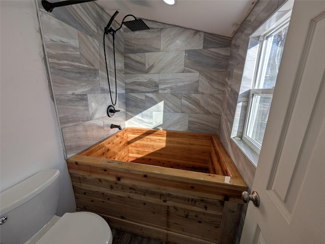 full bathroom with a tile shower and toilet