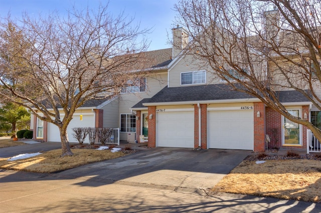 view of front of property featuring a shingled roof, a chimney, concrete driveway, and brick siding