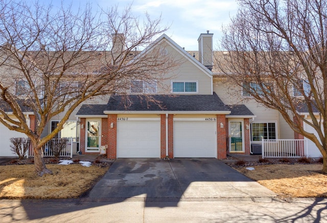 townhome / multi-family property featuring a chimney, a porch, concrete driveway, and brick siding