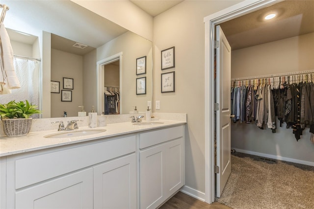 full bathroom featuring visible vents, a sink, a spacious closet, and double vanity