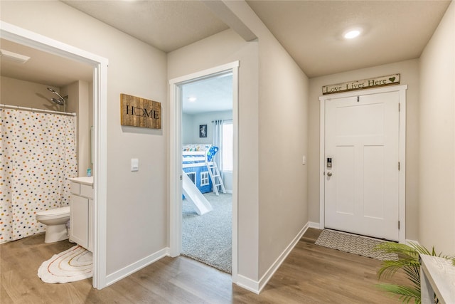 foyer with light wood-style flooring and baseboards