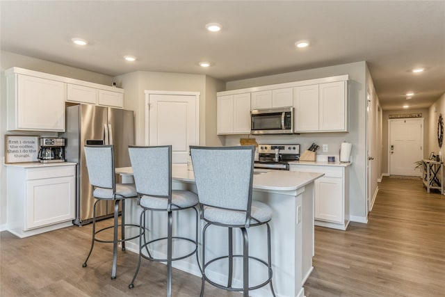 kitchen featuring a center island with sink, a breakfast bar area, stainless steel appliances, and light countertops