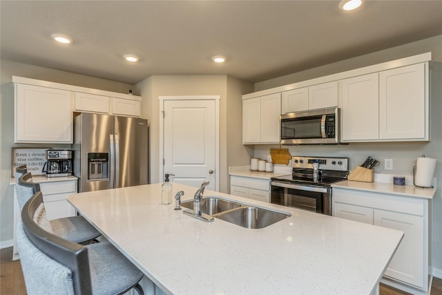 kitchen featuring an island with sink, appliances with stainless steel finishes, a sink, and recessed lighting