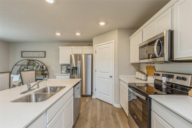 kitchen with stainless steel appliances, recessed lighting, light wood-style floors, white cabinetry, and a sink