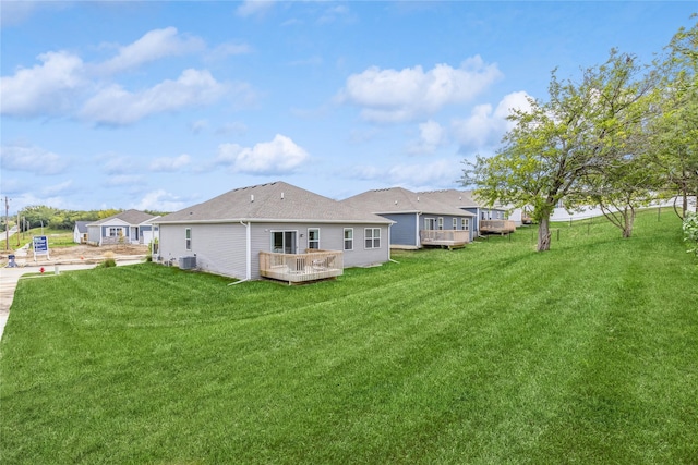 rear view of house with a lawn, a wooden deck, and central air condition unit