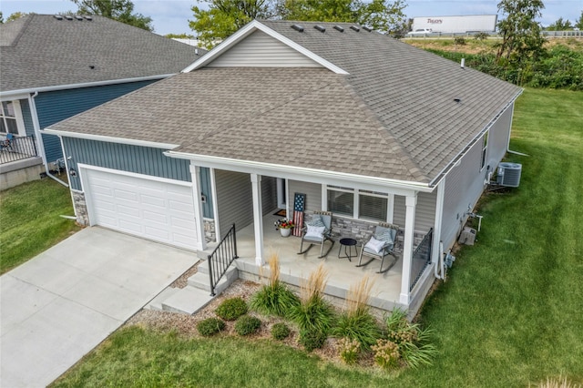 view of front of property featuring a garage, stone siding, a shingled roof, and a front yard