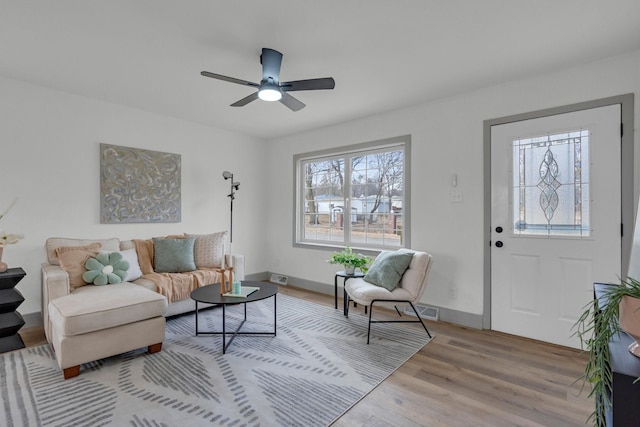 living room with visible vents, wood finished floors, a ceiling fan, and baseboards