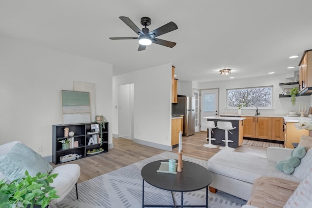 living area with baseboards, light wood-type flooring, a ceiling fan, and recessed lighting