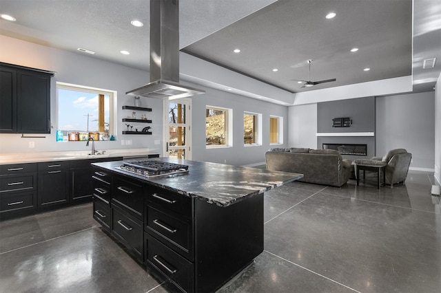 kitchen featuring finished concrete floors, stainless steel gas cooktop, dark cabinetry, and island exhaust hood