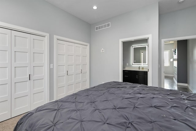 unfurnished bedroom with baseboards, visible vents, ensuite bathroom, multiple closets, and recessed lighting