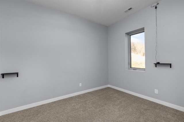 spare room featuring carpet floors, baseboards, and visible vents