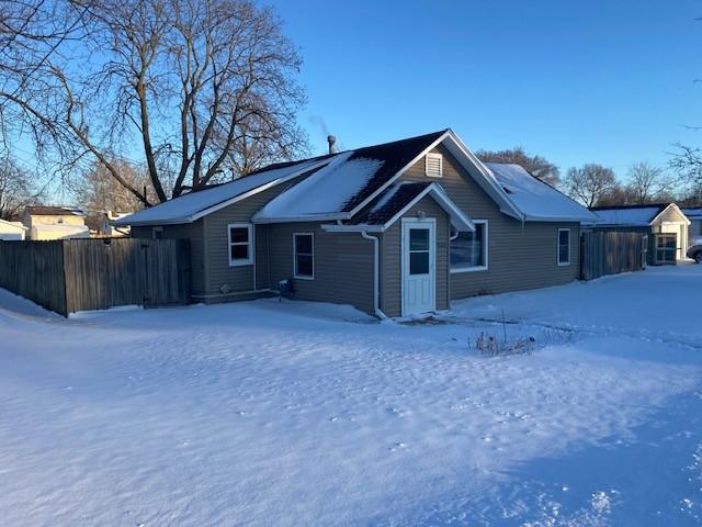 snow covered house featuring fence