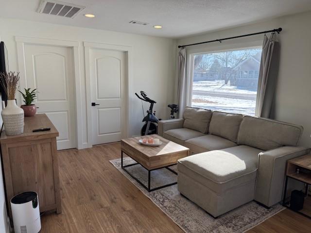 living area with light wood-style flooring, visible vents, and recessed lighting