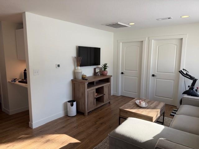 living area featuring baseboards, visible vents, wood finished floors, and recessed lighting