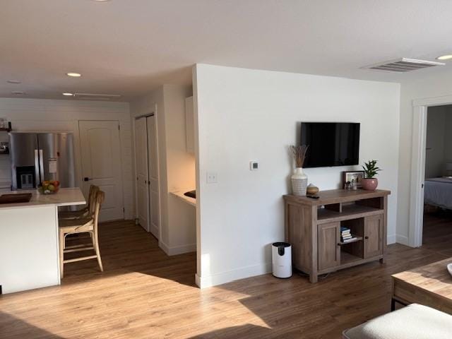 living room with wood finished floors, visible vents, and baseboards