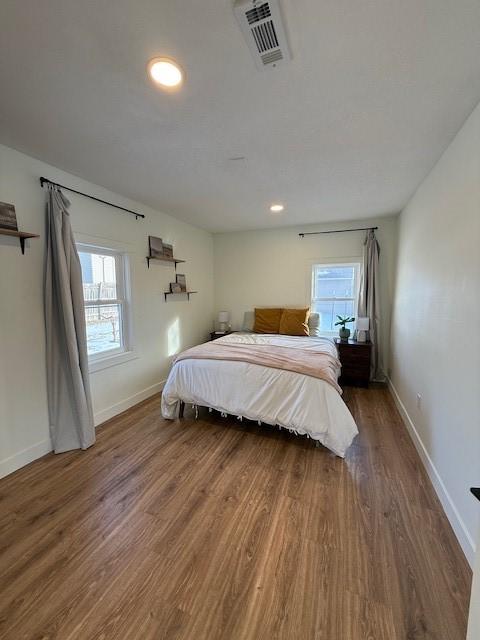 bedroom featuring visible vents, multiple windows, and wood finished floors