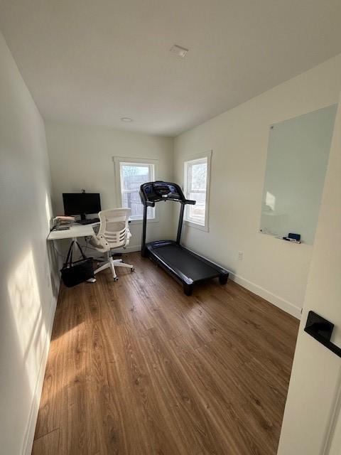 exercise area featuring dark wood-type flooring and baseboards