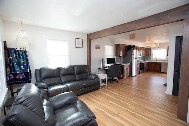 living area with light wood-type flooring and beam ceiling