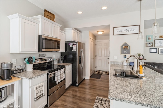 kitchen featuring appliances with stainless steel finishes, dark wood finished floors, white cabinetry, and a sink