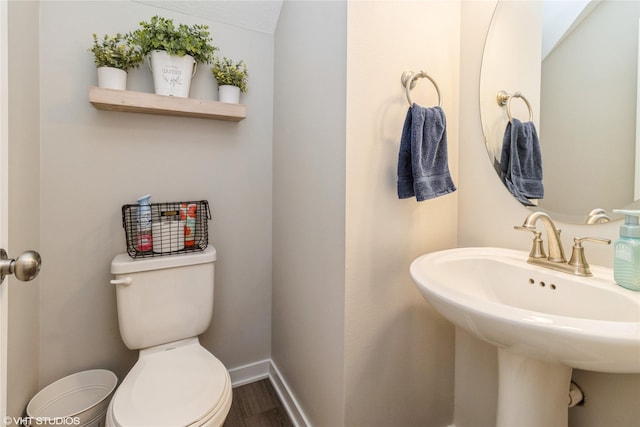 bathroom featuring a sink, toilet, baseboards, and wood finished floors