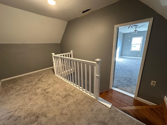 staircase with baseboards, visible vents, lofted ceiling, wood finished floors, and carpet flooring