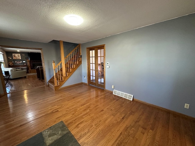 spare room featuring french doors, visible vents, stairway, and wood finished floors