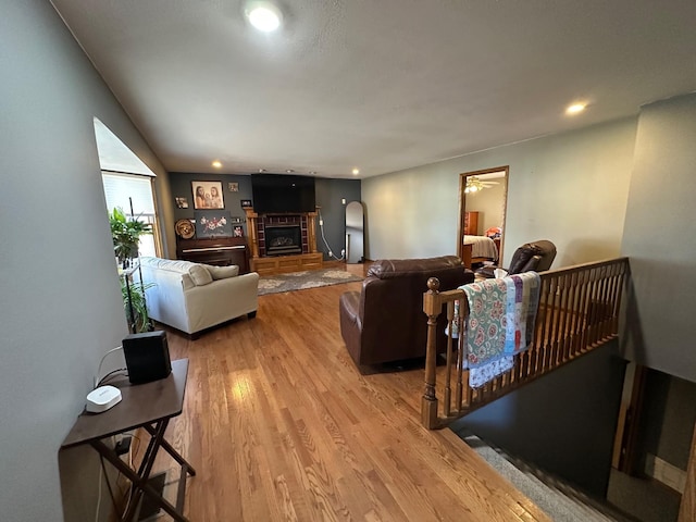 living area featuring a glass covered fireplace, light wood-style flooring, and recessed lighting