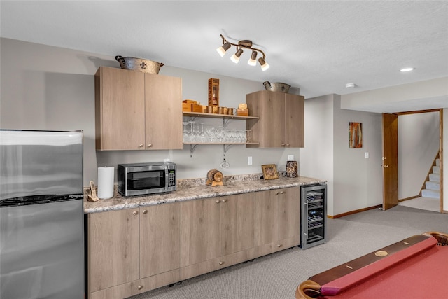 kitchen with wine cooler, light colored carpet, light brown cabinetry, appliances with stainless steel finishes, and baseboards