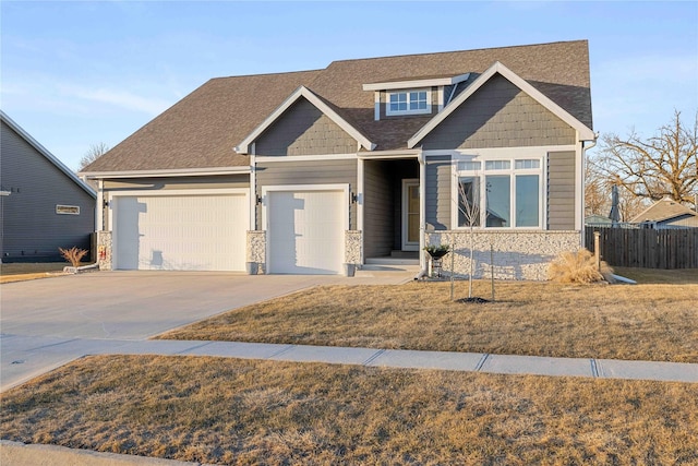 craftsman-style home with a garage, driveway, roof with shingles, fence, and a front lawn