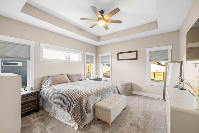 bedroom featuring baseboards, a tray ceiling, and light colored carpet