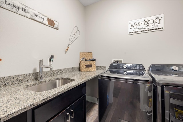 clothes washing area featuring wood finished floors, separate washer and dryer, a sink, and cabinet space