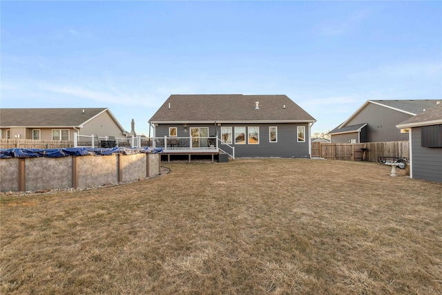 back of house with a deck, a lawn, fence, and a covered pool