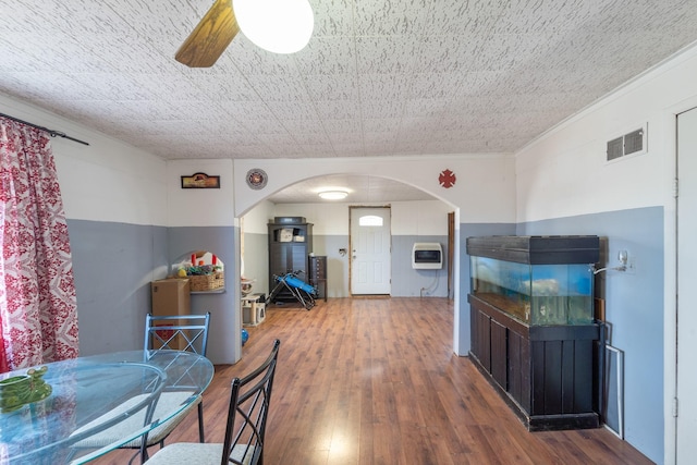 dining space featuring arched walkways, ceiling fan, visible vents, heating unit, and wood-type flooring