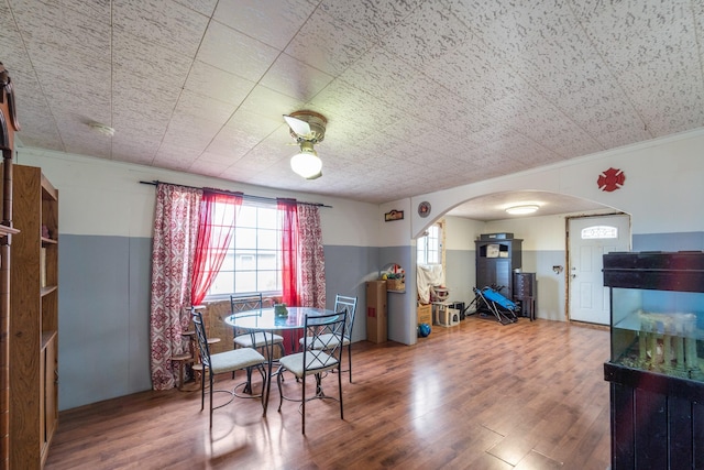 dining space with arched walkways and wood finished floors