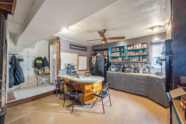 bar featuring a ceiling fan, light floors, black refrigerator with ice dispenser, stainless steel microwave, and cooktop