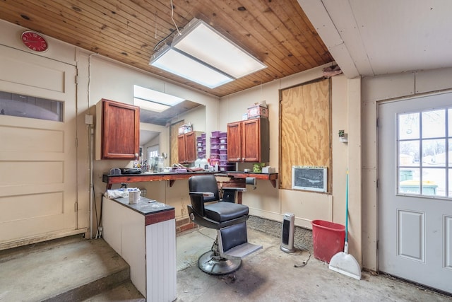 kitchen with brown cabinetry, dark countertops, concrete floors, and a peninsula