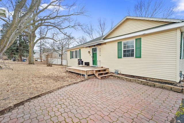 back of house with a wooden deck and a patio