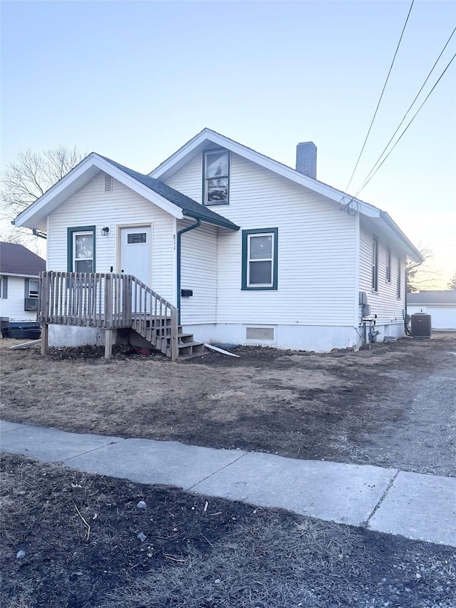 view of front of property featuring a chimney and central air condition unit