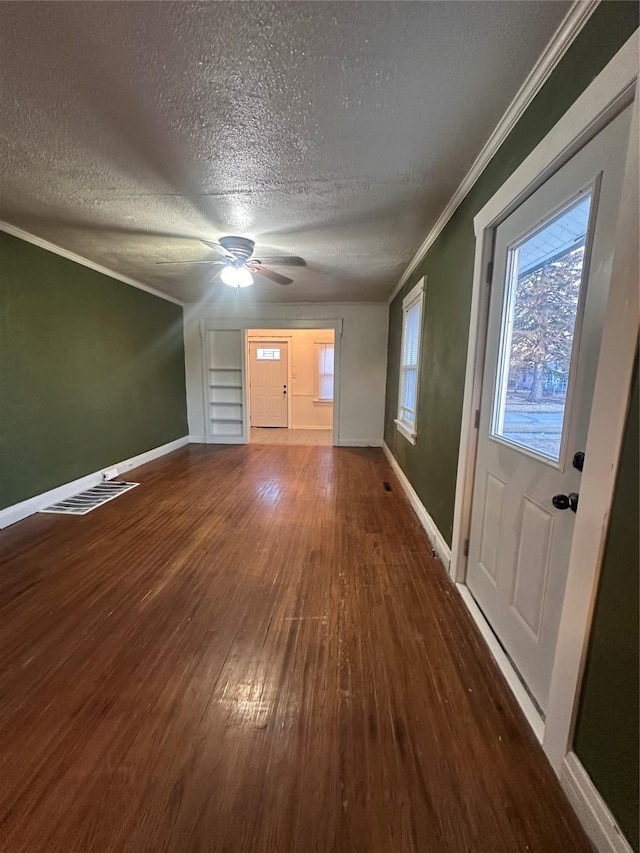 unfurnished living room featuring a healthy amount of sunlight, baseboards, ornamental molding, and wood finished floors