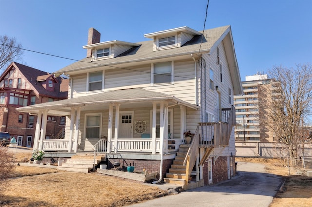 american foursquare style home featuring covered porch and a chimney