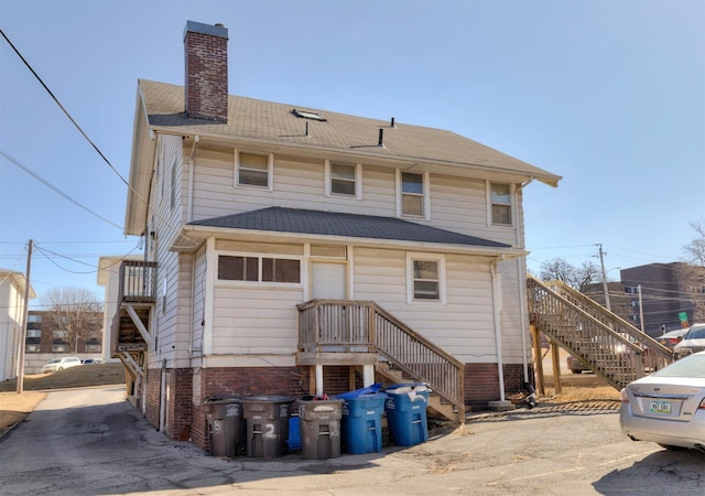 back of property featuring roof with shingles and a chimney