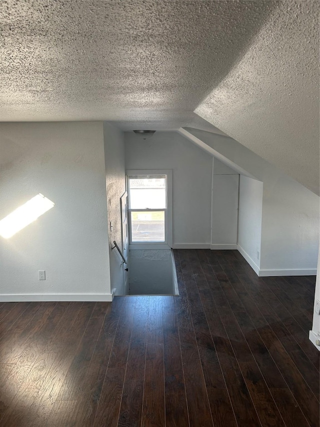 additional living space featuring lofted ceiling, baseboards, a textured ceiling, and hardwood / wood-style floors