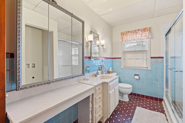 full bath featuring toilet, tile patterned flooring, wainscoting, a shower stall, and vanity