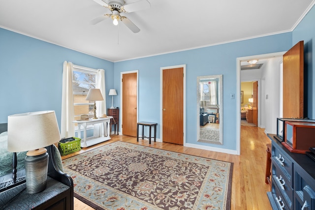 sitting room featuring ceiling fan, baseboards, light wood-style flooring, and crown molding