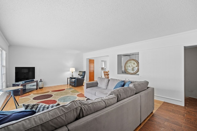 living room featuring ornamental molding, wood finished floors, and a textured ceiling